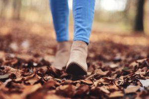 human legs walking through autumnal leaves